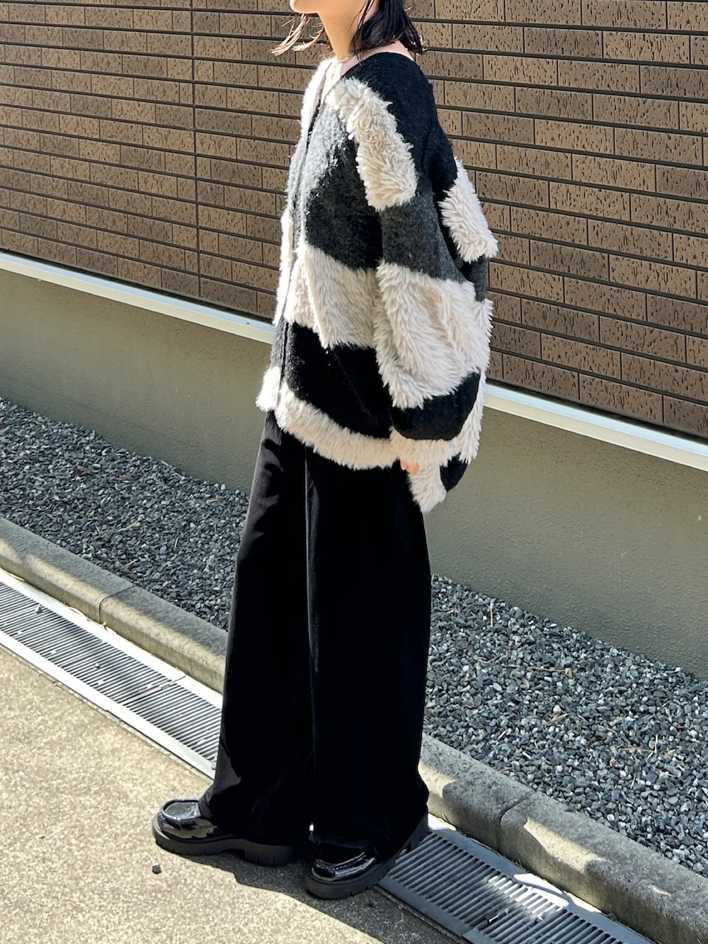 ブラック系のカーディガン/ボレロ、ブラック系のパンツ、ブラック系のローファーを着用したレディースの秋コーディネートの4枚目の写真