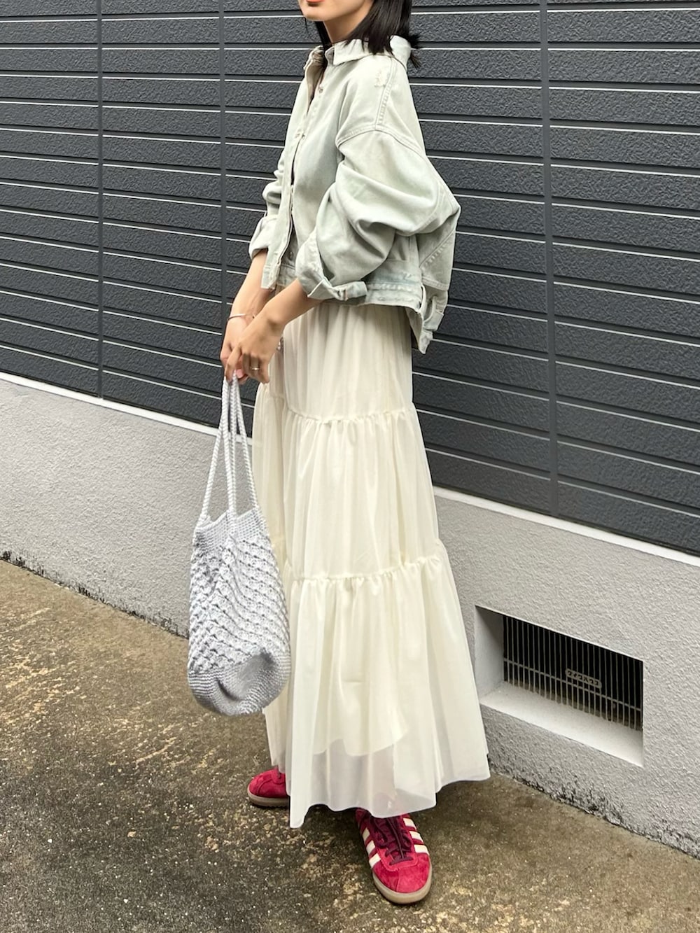 ブルー系のデニムジャケット、ホワイト系のキャミソール、ホワイト系のスカートを着用したレディースの春コーディネートの4枚目の写真