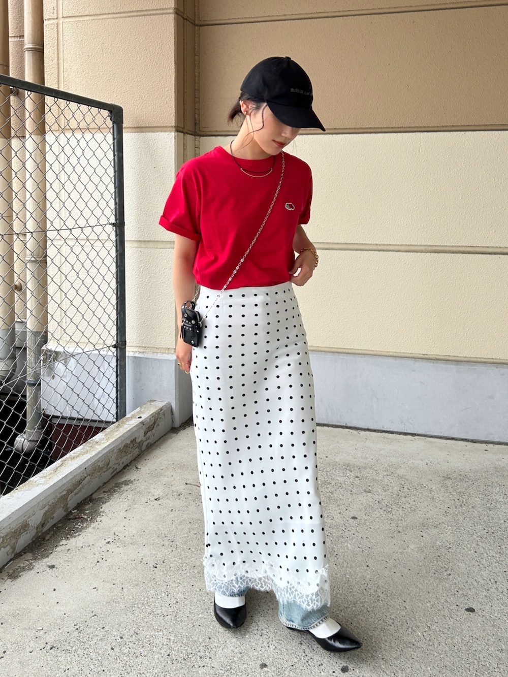 レッド系のTシャツ/カットソー、ホワイト系のスカート、ブラック系のパンプスを着用したレディースの春コーディネートの3枚目の写真