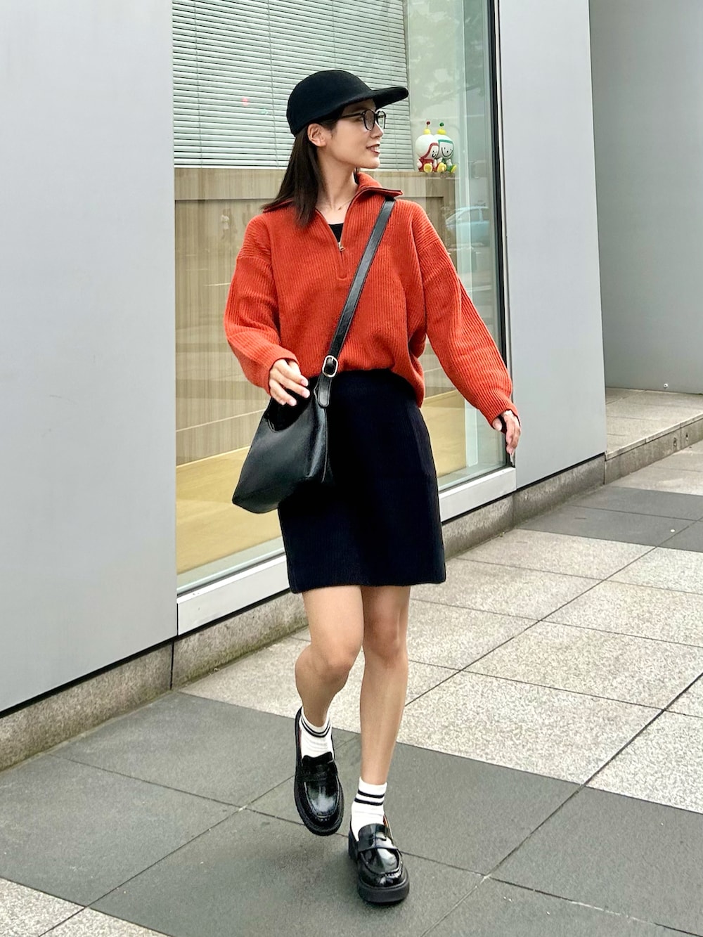 ブラック系のハンドバッグ、オレンジ系のニット/セーター、ブラック系のローファーを着用したレディースの秋コーディネートの2枚目の写真