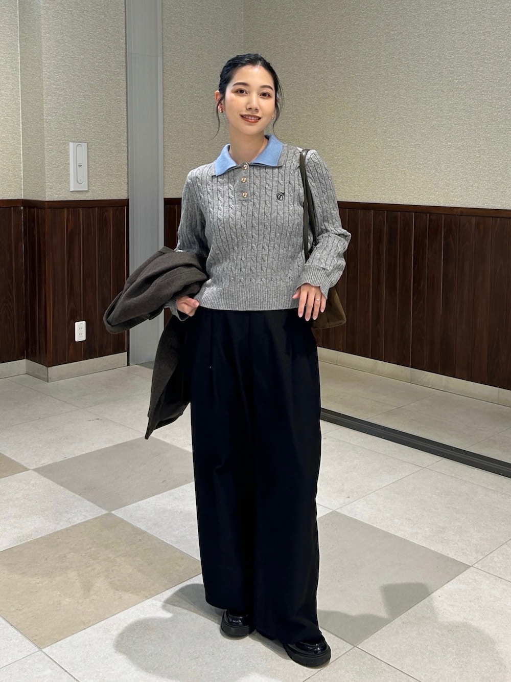 グレー系のニット/セーター、ブラウン系のテーラードジャケット、グリーン系のハンドバッグを着用したレディースの冬コーディネートの2枚目の写真