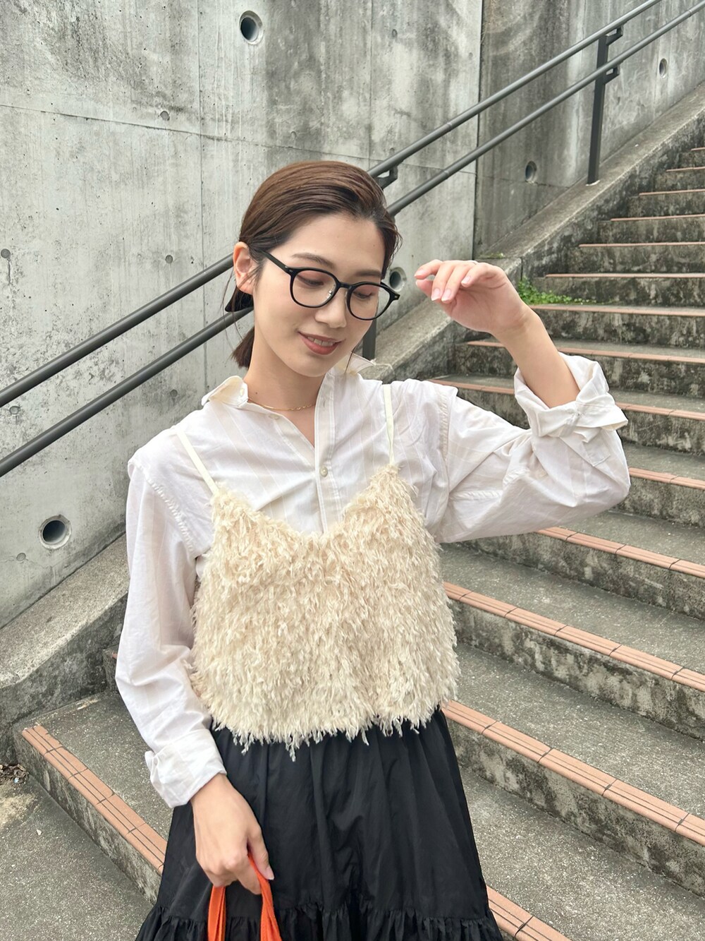 ホワイト系のベスト、ブラック系のスカート、ブラック系のローファーを着用したレディースの春コーディネートの3枚目の写真