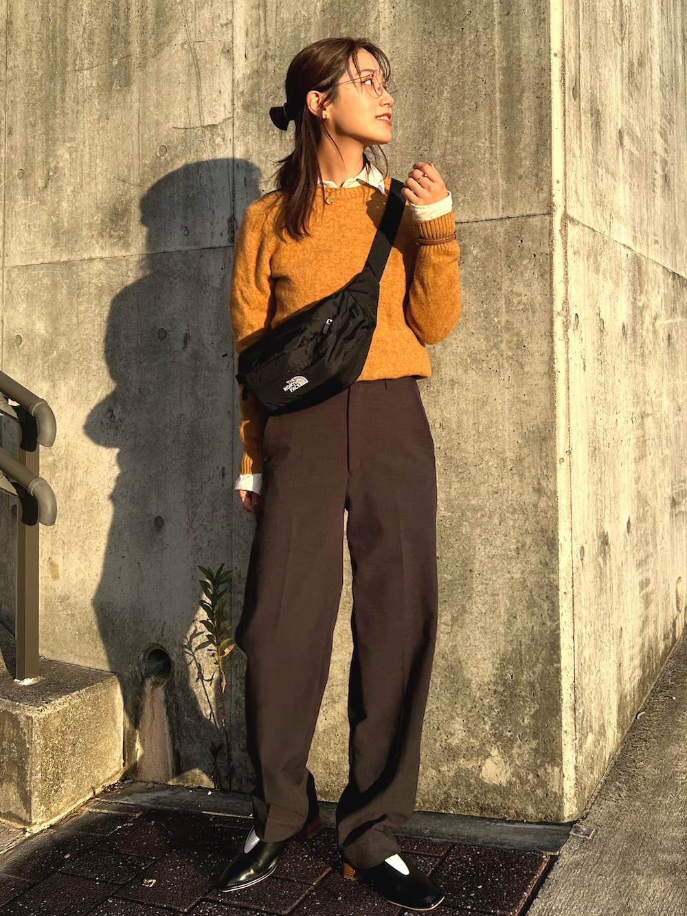 ブラック系のパンプス、グレー系のパンツ、ブラック系のボディバッグ/ウエストポーチを着用したレディースの秋コーディネートの2枚目の写真