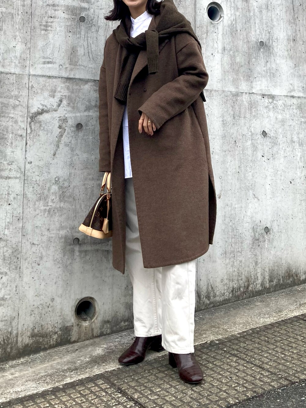 ホワイト系のデニムパンツ、ブラウン系のノーカラーコート、ブラウン系のニット/セーターを着用したレディースの冬コーディネートの2枚目の写真