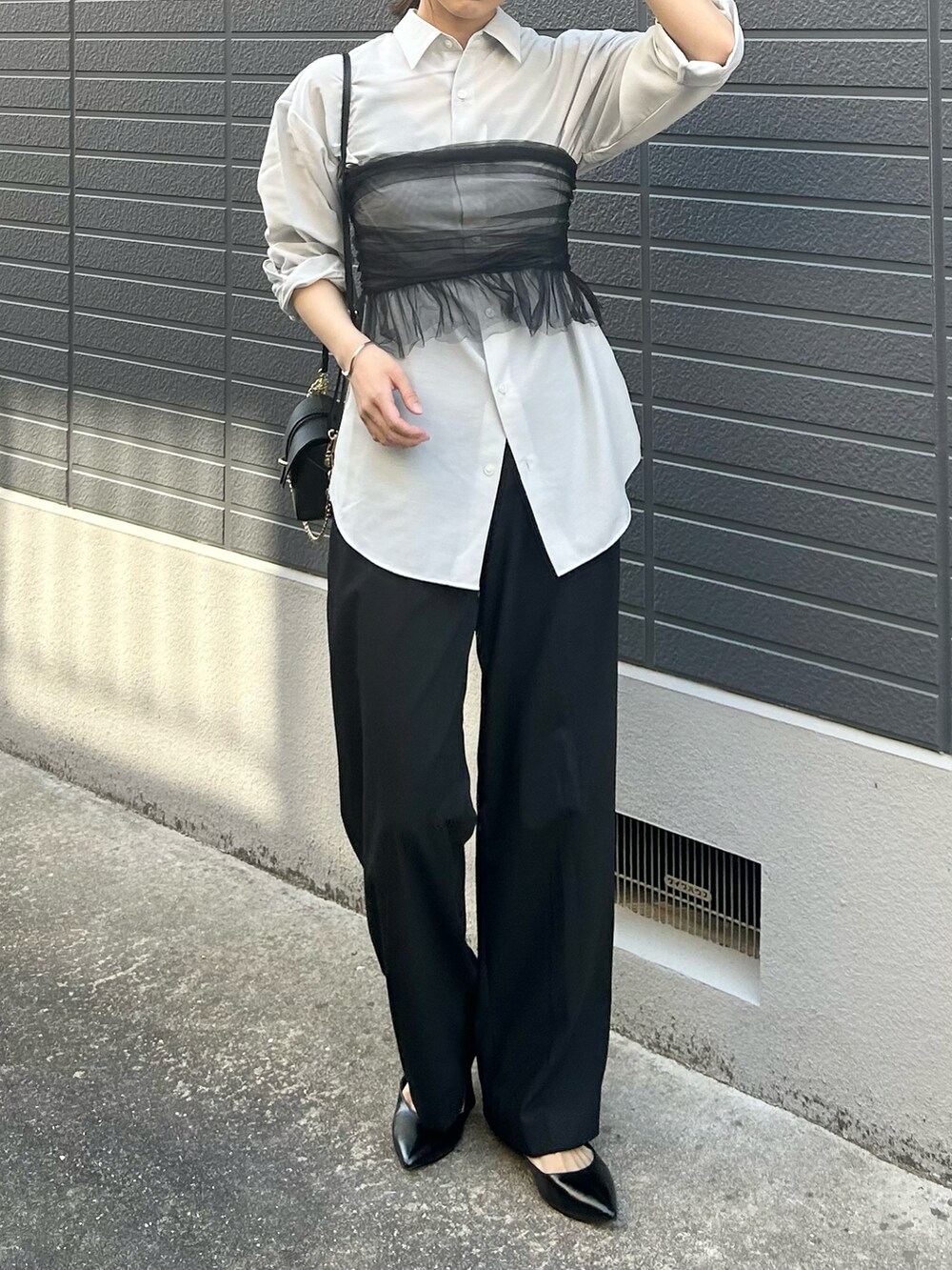 ブラック系のシャツ/ブラウス、ブラック系のパンプス、ブラック系のショルダーバッグを着用したレディースの春コーディネートの2枚目の写真