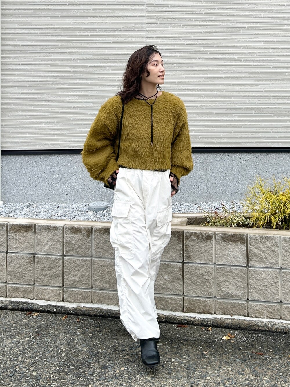 グリーン系のニット/セーター、ブラック系のTシャツ/カットソー、ホワイト系のカーゴパンツを着用したレディースの冬コーディネートの3枚目の写真