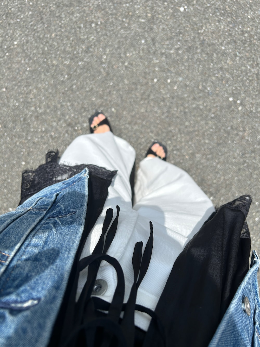 ブラック系のキャミソール、ブラック系のハンドバッグ、ホワイト系のデニムパンツを着用したレディースの春コーディネートの4枚目の写真