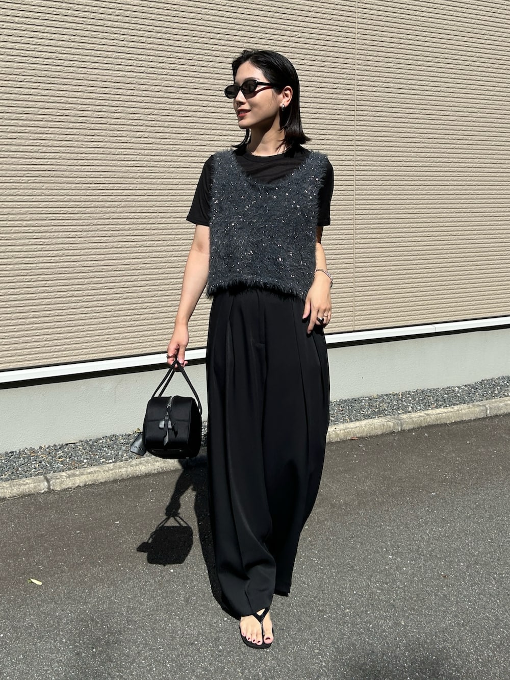 グレー系のベスト、ブラック系のボストンバッグ、ブラック系のサンダルを着用したレディースの夏コーディネートの3枚目の写真