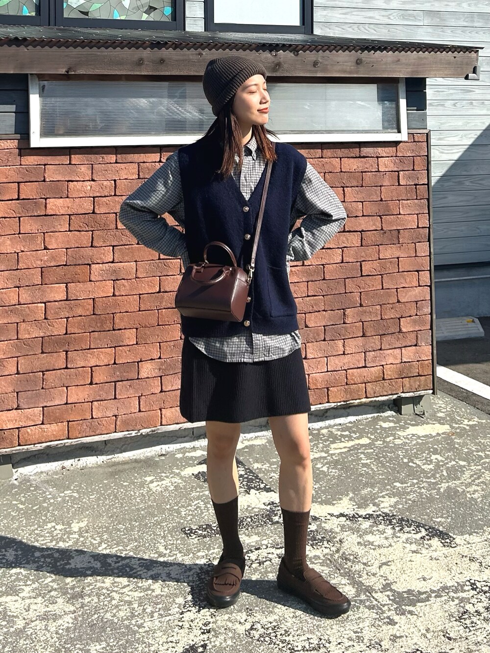 ブルー系のベスト、グレー系のシャツ/ブラウス、ブラウン系のボストンバッグを着用したレディースの秋コーディネートの2枚目の写真