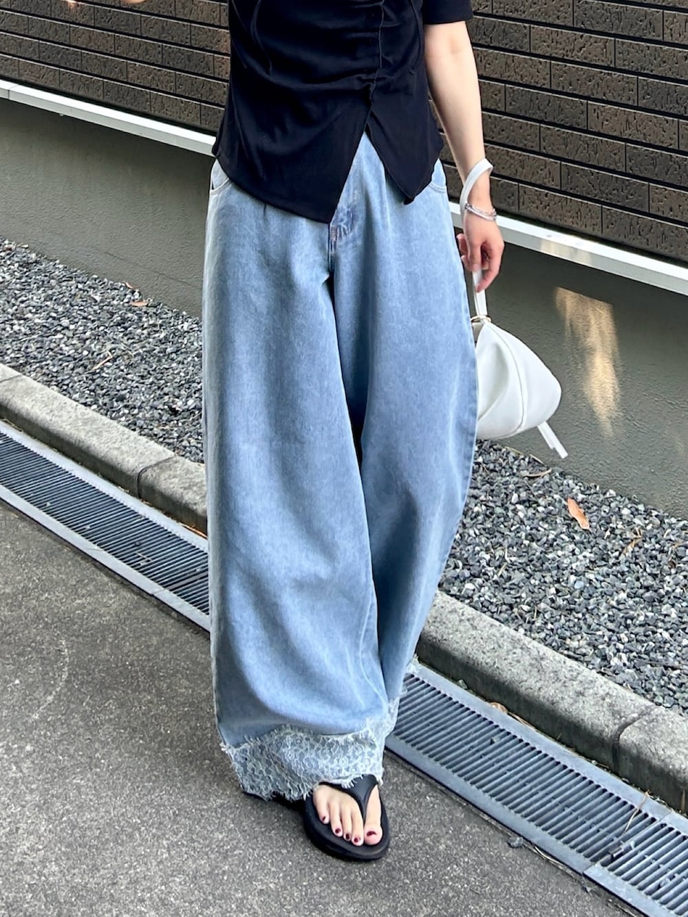 ブラック系のTシャツ/カットソー、ブルー系のデニムパンツ、ブラック系のサンダルを着用したレディースの夏コーディネートの4枚目の写真