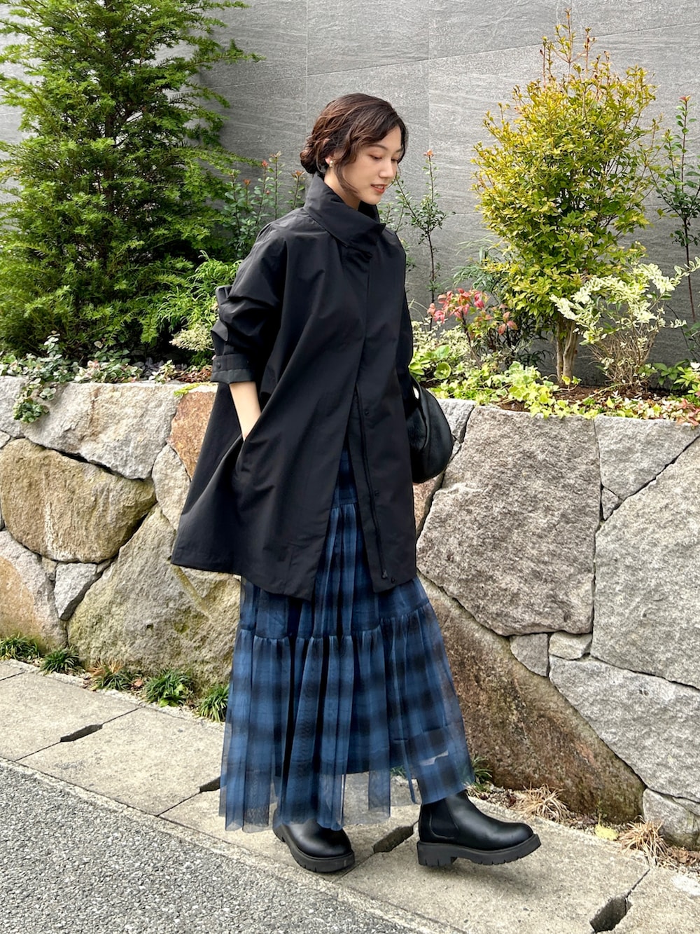 ブルー系のスカート、ブラック系のブーツ、ブラック系のハンドバッグを着用したレディースの秋コーディネートの2枚目の写真