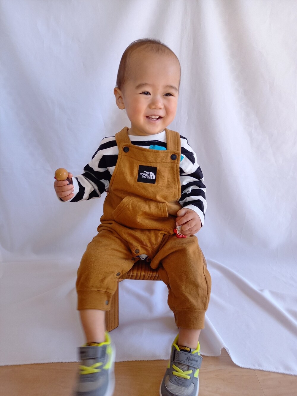 グリーン系のスニーカー、ブラウン系のオールインワン・サロペット、ホワイト系のTシャツ/カットソーを着用したキッズの春コーディネートの2枚目の写真