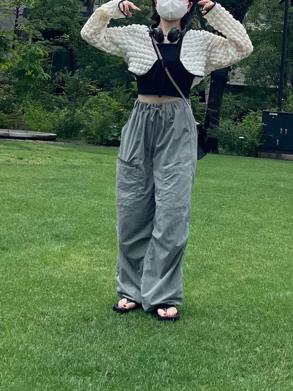 グリーン系のパンツ、ブラック系のサンダル、ホワイト系のトップスを着用したレディースの夏コーディネートの2枚目の写真