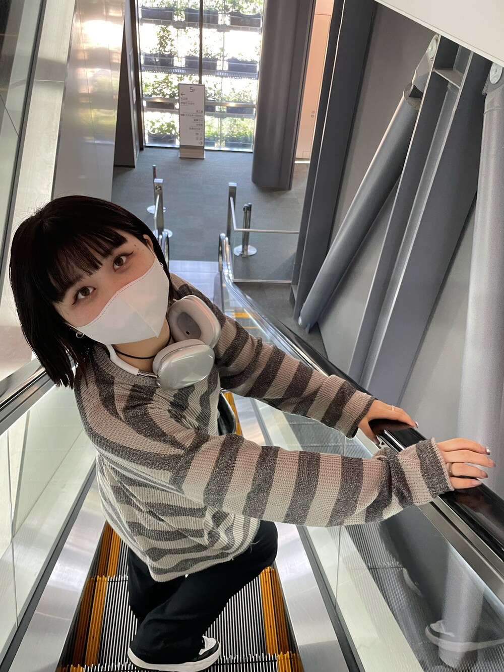 グレー系のトップス、ブラック系のスニーカー、ホワイト系のヘッドフォン/イヤホンを着用したレディースの秋コーディネートの3枚目の写真