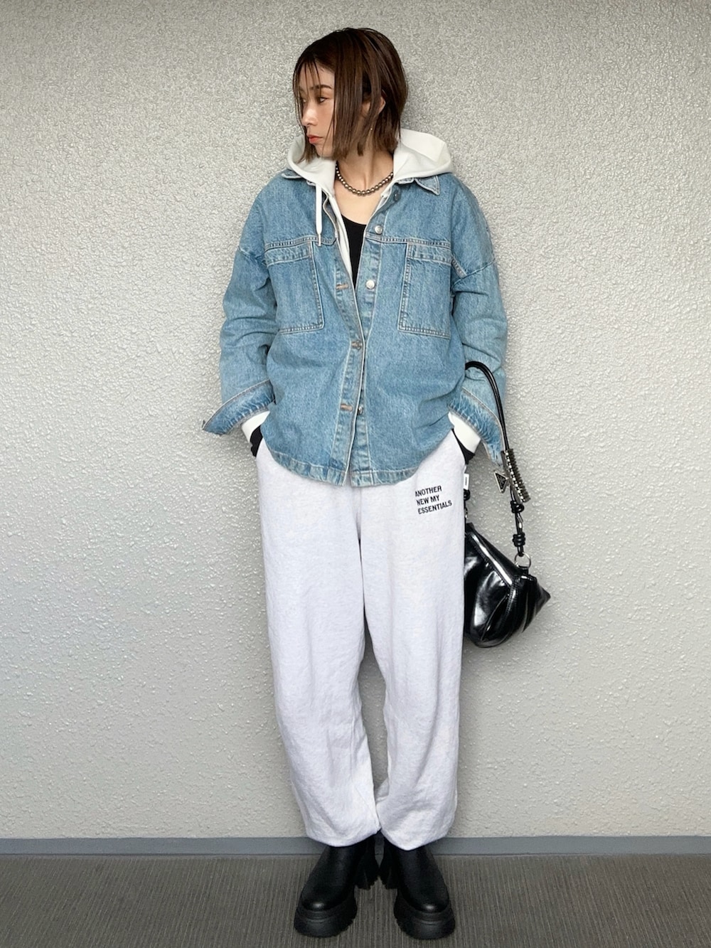 ブラック系のブーツ、ブラック系のハンドバッグ、ベージュ系のスウェットパンツを着用したレディースの秋コーディネートの3枚目の写真