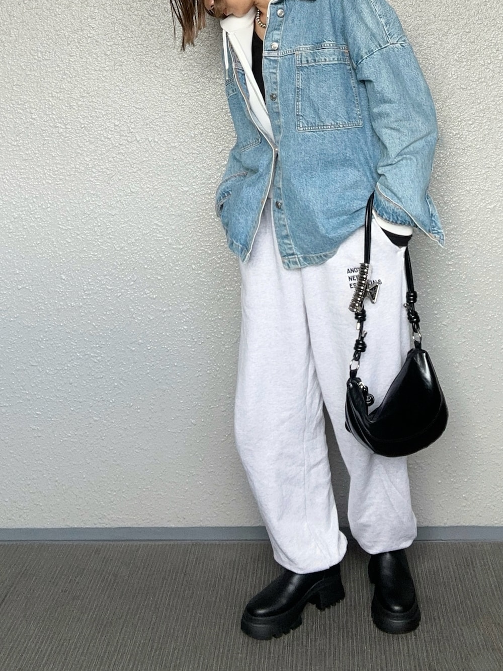 ブラック系のブーツ、ブラック系のハンドバッグ、ベージュ系のスウェットパンツを着用したレディースの秋コーディネートの2枚目の写真