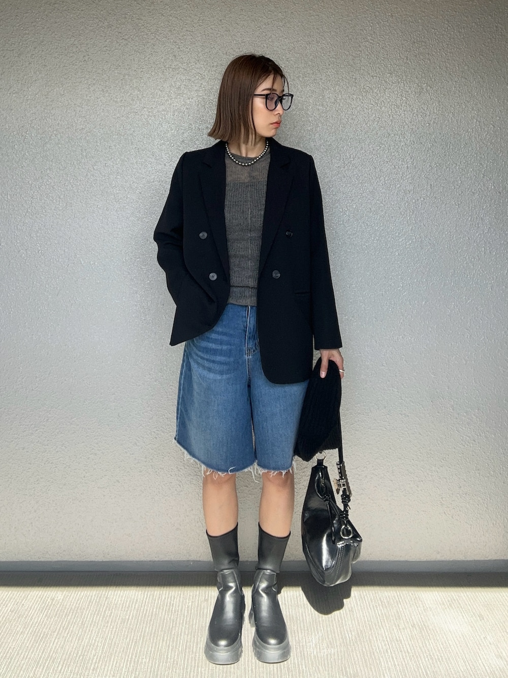 ブラック系のハンドバッグ、グレー系のニット/セーター、ブラック系のテーラードジャケットを着用したレディースの秋コーディネートの2枚目の写真