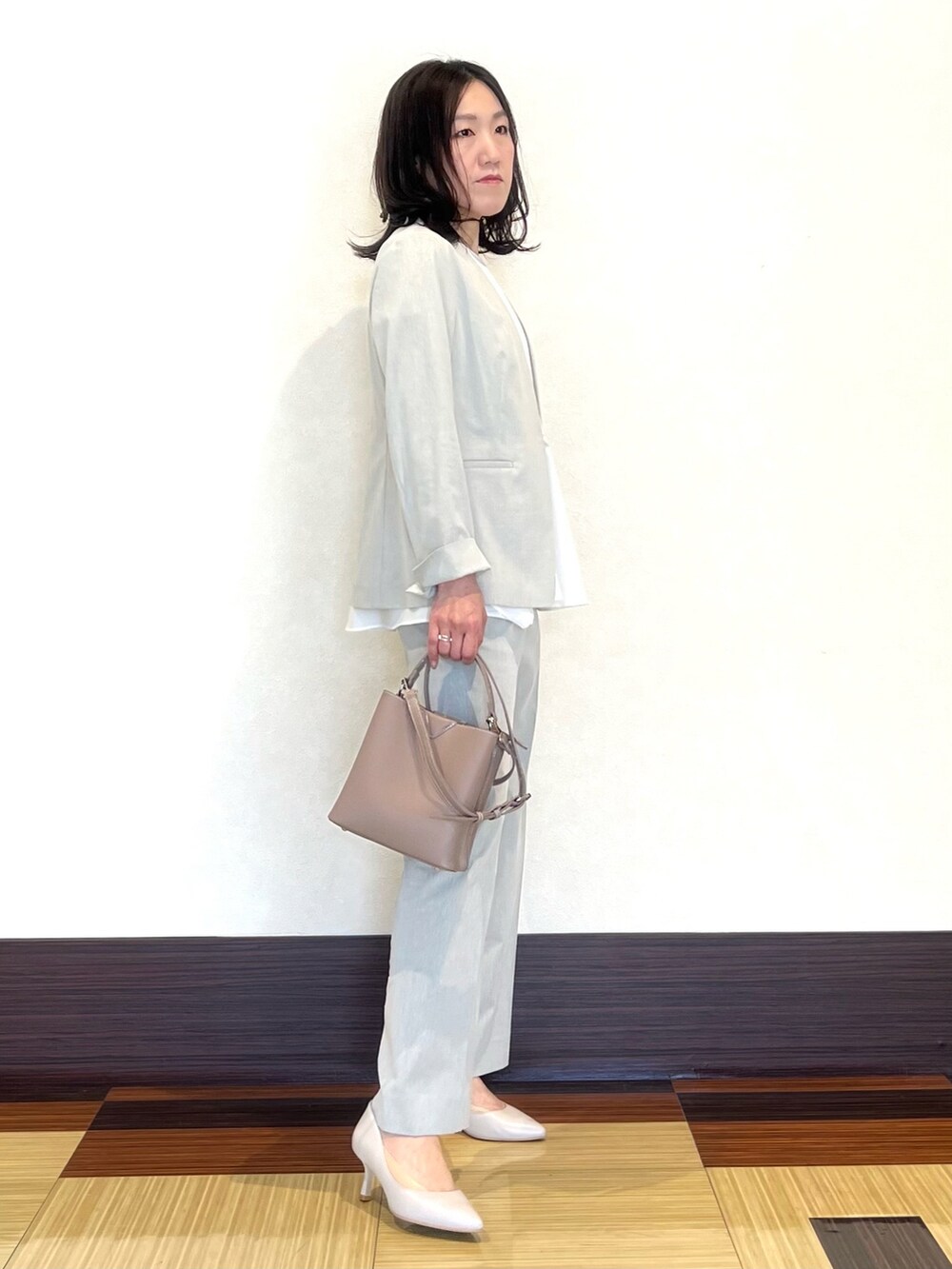 グレー系のスーツジャケット、ホワイト系のシャツ/ブラウス、グレー系のスーツパンツを着用したレディースの春コーディネートの3枚目の写真