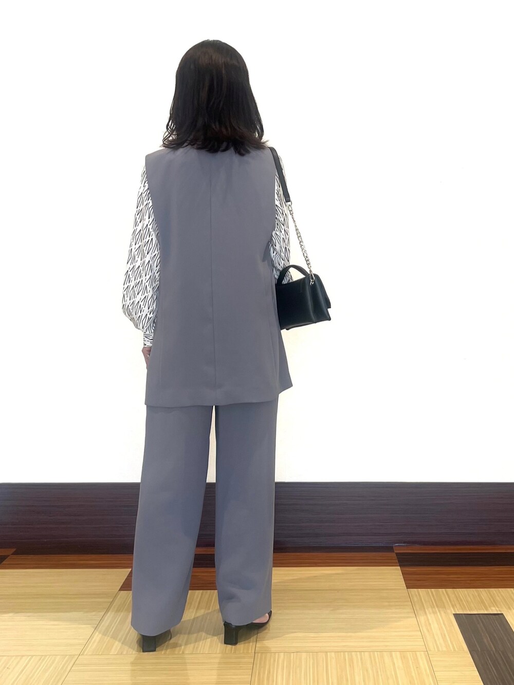 グレー系のベスト、ホワイト系のシャツ/ブラウス、グレー系のスーツパンツを着用したレディースの秋コーディネートの5枚目の写真