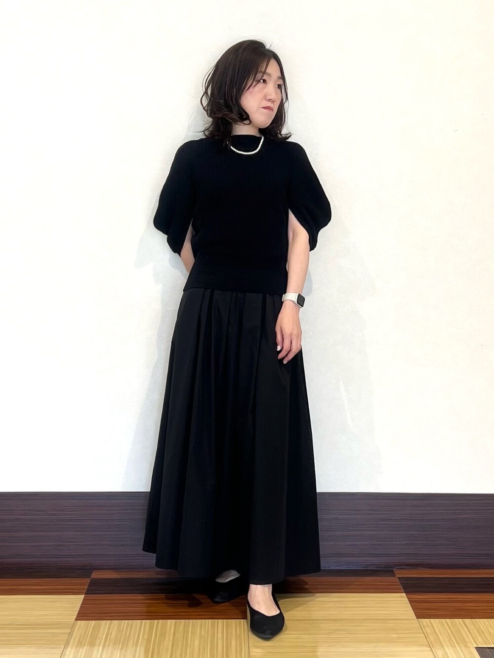 ブラック系のニット/セーター、ブラック系のスカート、ブラック系のパンプスを着用したレディースの夏コーディネートの3枚目の写真