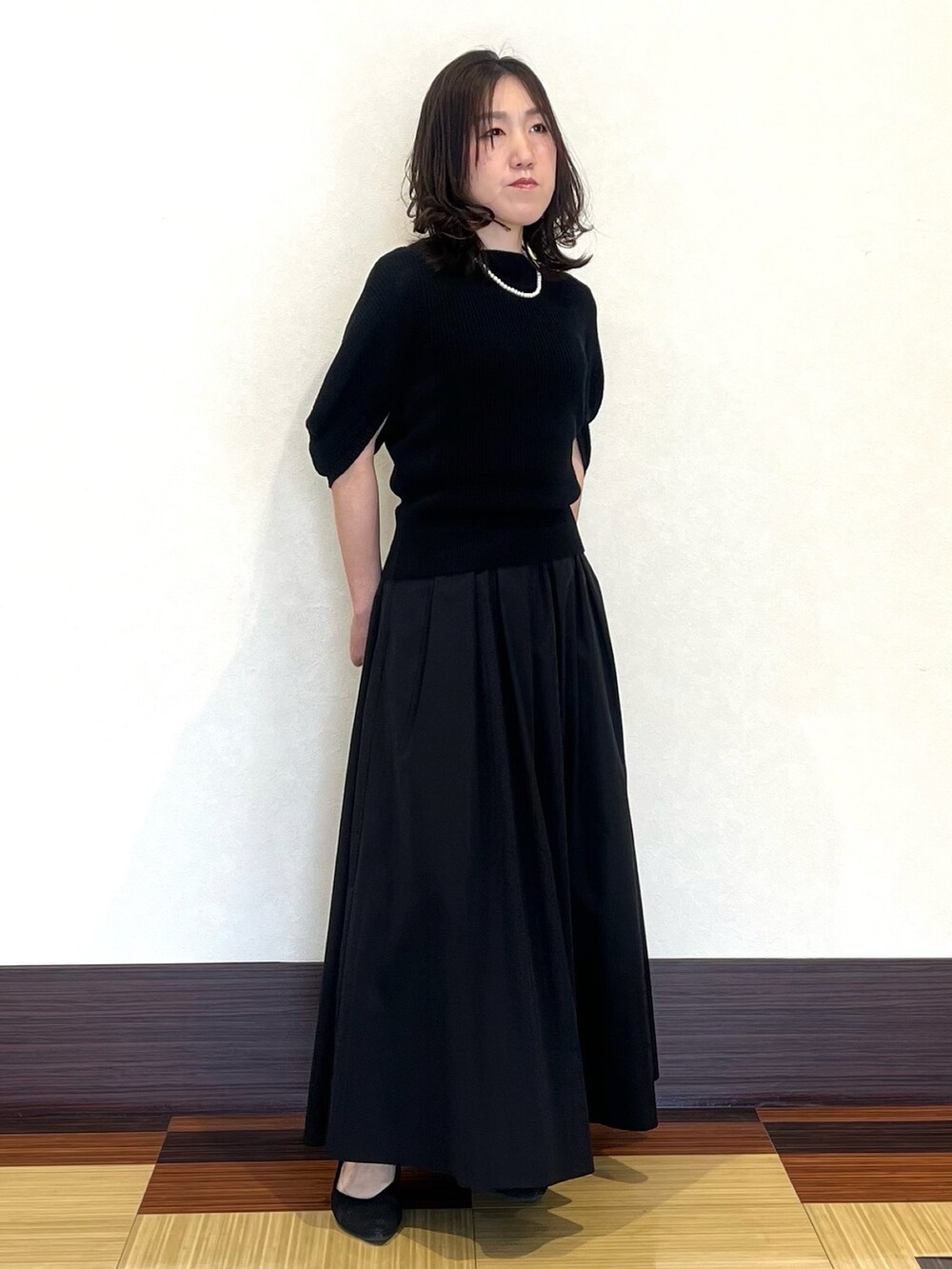 ブラック系のニット/セーター、ブラック系のスカート、ブラック系のパンプスを着用したレディースの夏コーディネートの2枚目の写真
