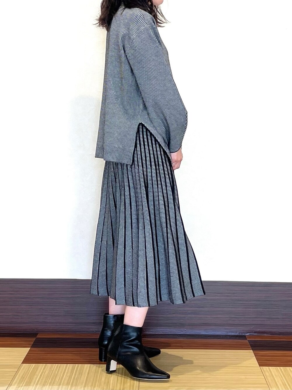 ブラック系のニット/セーター、ブラック系のスカート、ブラック系のブーツを着用したレディースの秋コーディネートの4枚目の写真