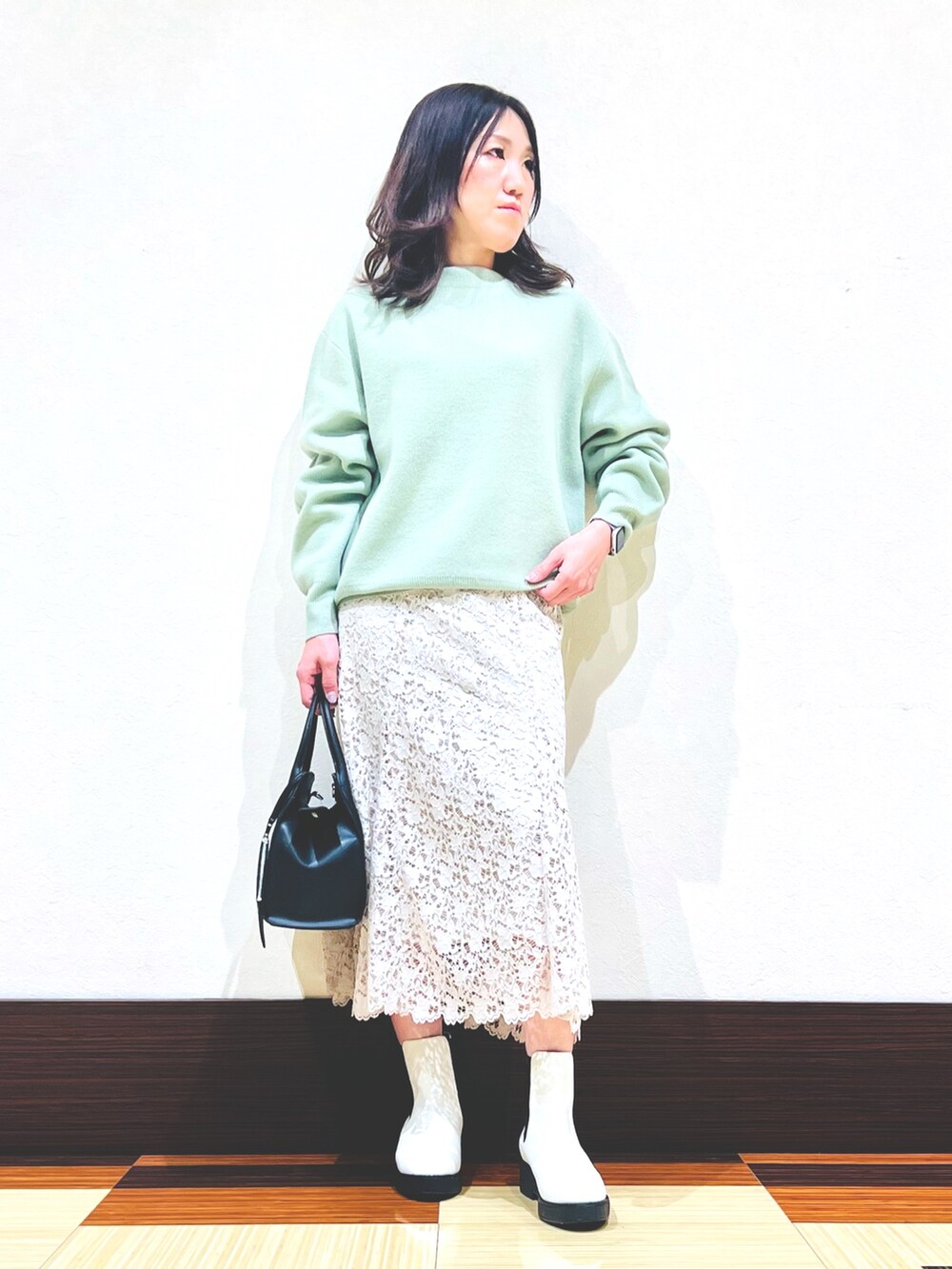 グリーン系のニット/セーター、ホワイト系のブーツ、ベージュ系のスカートを着用したレディースの冬コーディネートの3枚目の写真