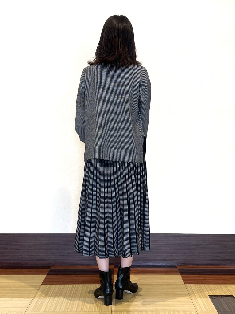 ブラック系のニット/セーター、ブラック系のスカート、ブラック系のブーツを着用したレディースの秋コーディネートの5枚目の写真