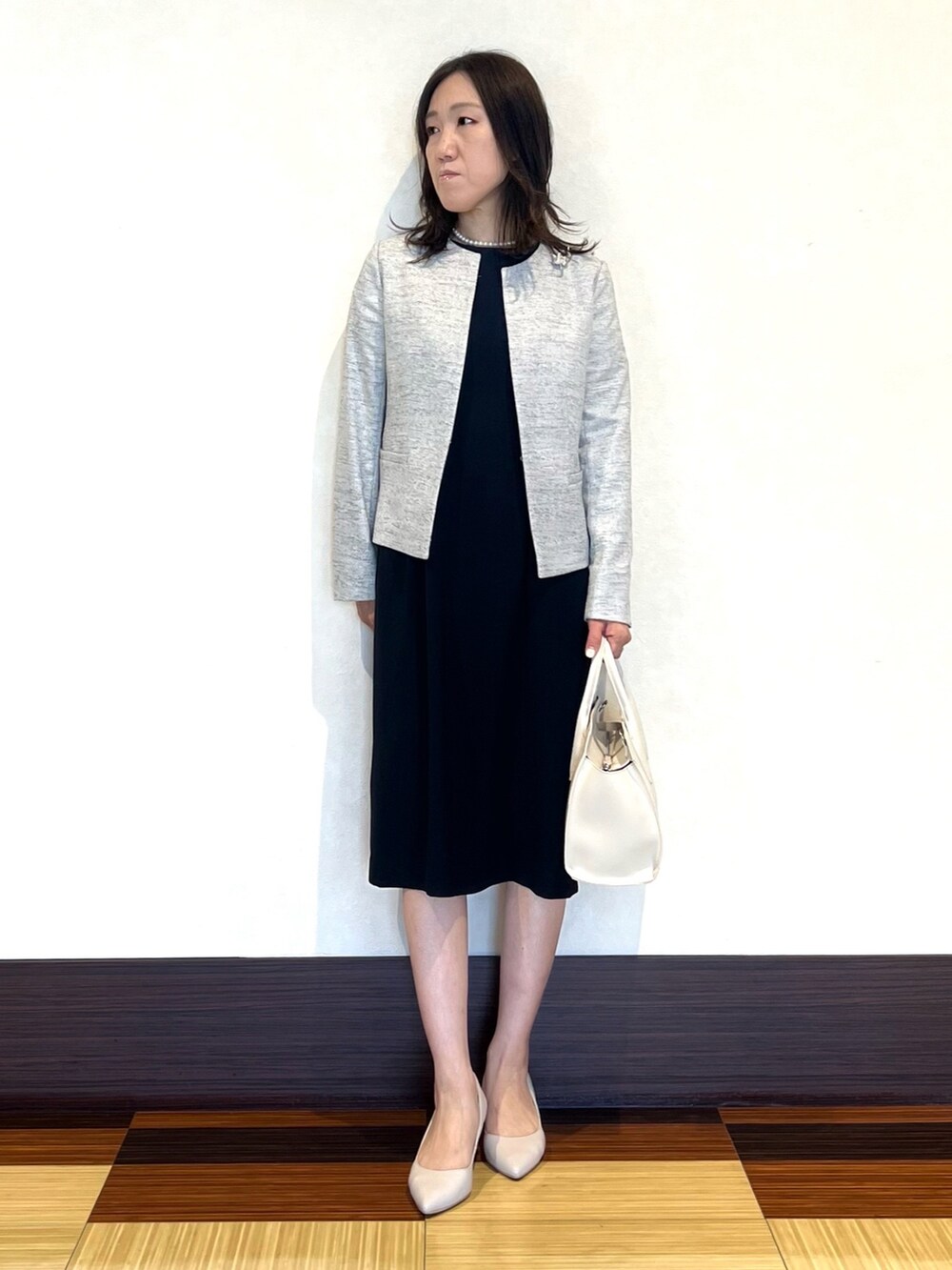 ブラック系のノーカラージャケット、ブルー系のワンピース、ホワイト系のショルダーバッグを着用したレディースの冬コーディネートの3枚目の写真