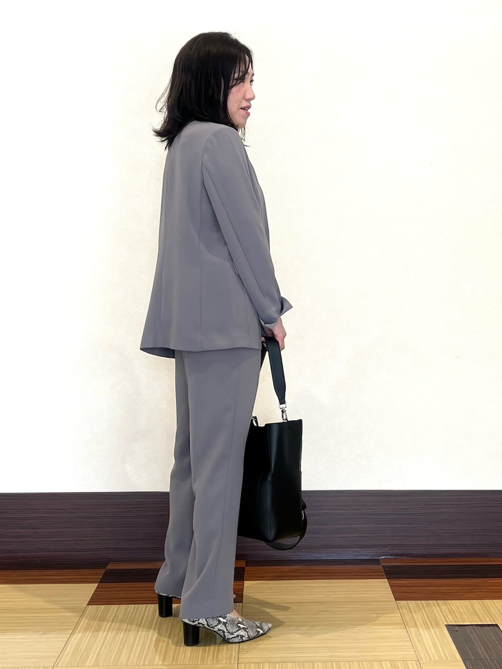 ブラック系のニット/セーター、グレー系のスーツジャケット、グレー系のスーツパンツを着用したレディースの秋コーディネートの4枚目の写真