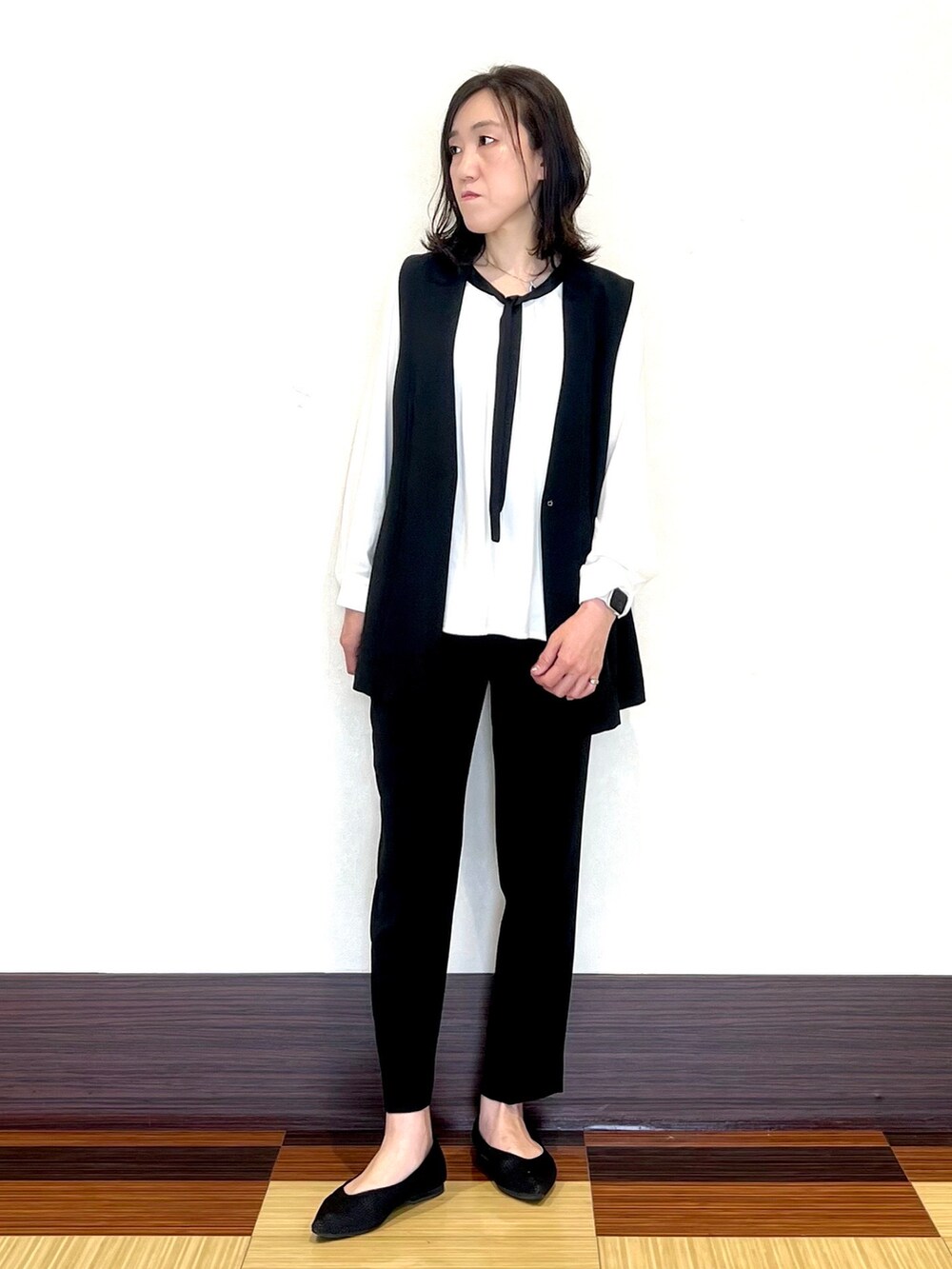 ホワイト系のシャツ/ブラウス、ブラック系のベスト、ブラック系のスーツパンツを着用したレディースの春コーディネートの3枚目の写真