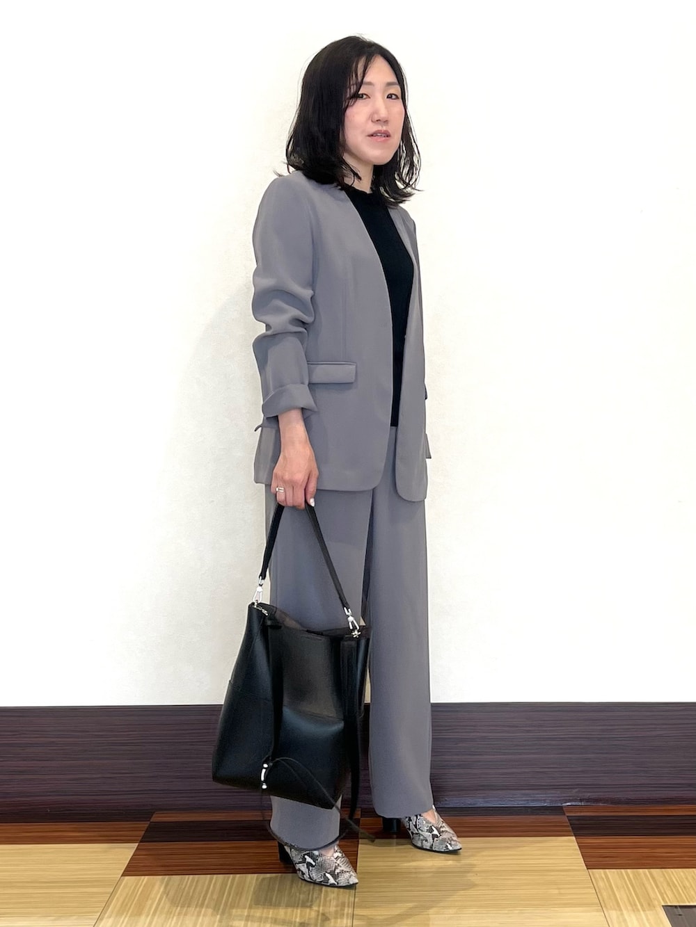 ブラック系のニット/セーター、グレー系のスーツジャケット、グレー系のスーツパンツを着用したレディースの秋コーディネートの2枚目の写真