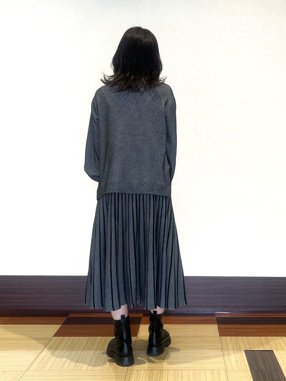 ブラック系のニット/セーター、ブラック系のスカート、ブラック系のブーツを着用したレディースの秋コーディネートの5枚目の写真