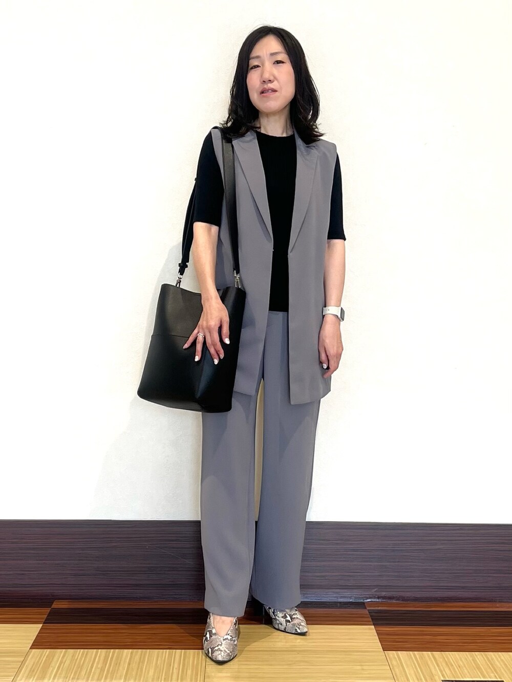 ブラック系のニット/セーター、グレー系のベスト、グレー系のスーツパンツを着用したレディースの秋コーディネートの2枚目の写真