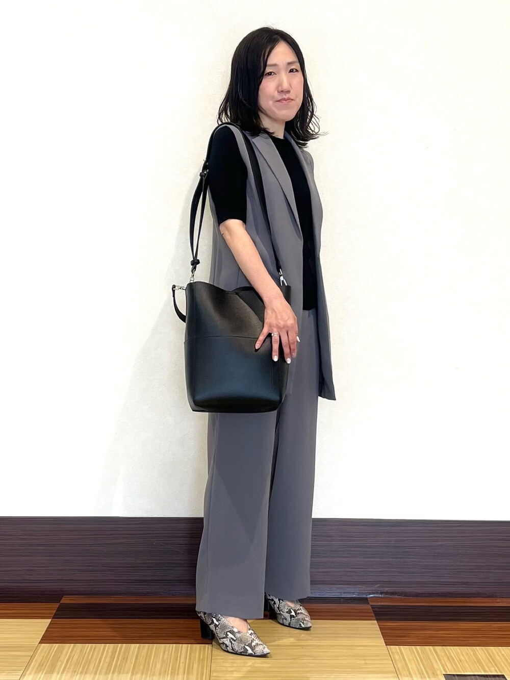 ブラック系のニット/セーター、グレー系のベスト、グレー系のスーツパンツを着用したレディースの秋コーディネートの3枚目の写真