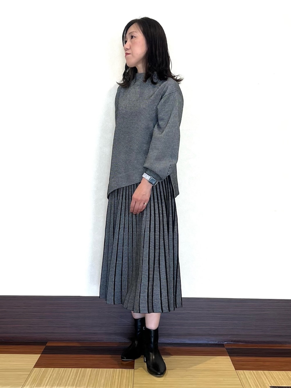 ブラック系のニット/セーター、ブラック系のスカート、ブラック系のブーツを着用したレディースの秋コーディネートの3枚目の写真