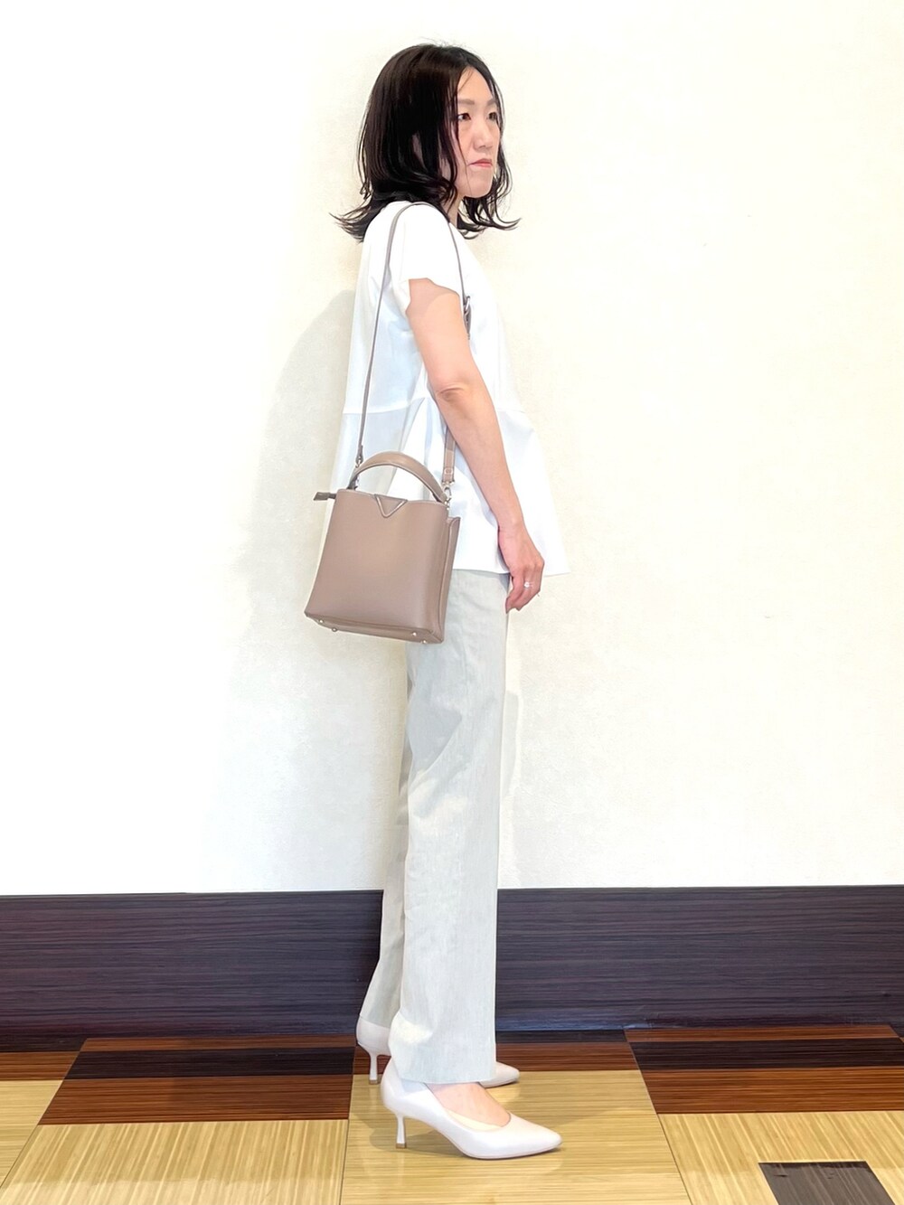 ホワイト系のシャツ/ブラウス、グレー系のスーツパンツ、ベージュ系のショルダーバッグを着用したレディースの夏コーディネートの3枚目の写真