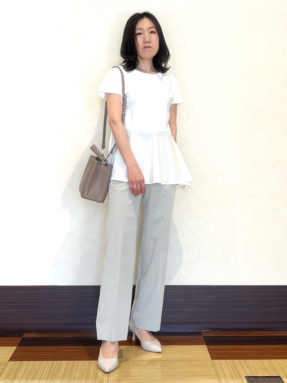 ホワイト系のシャツ/ブラウス、グレー系のスーツパンツ、ベージュ系のショルダーバッグを着用したレディースの夏コーディネートの2枚目の写真