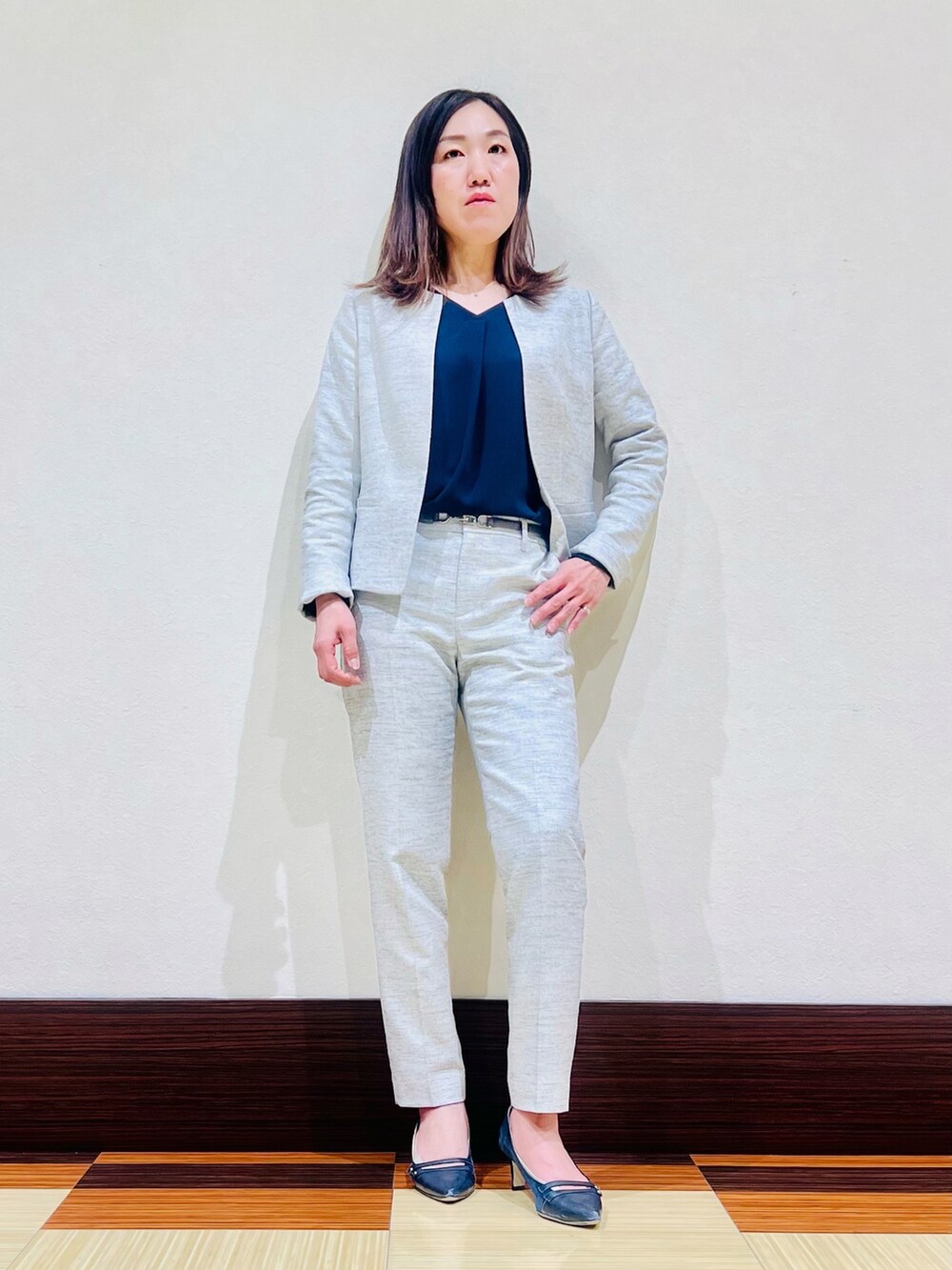 ホワイト系のスーツジャケット、ブルー系のシャツ/ブラウス、ブラック系のスーツパンツを着用したレディースの春コーディネートの2枚目の写真