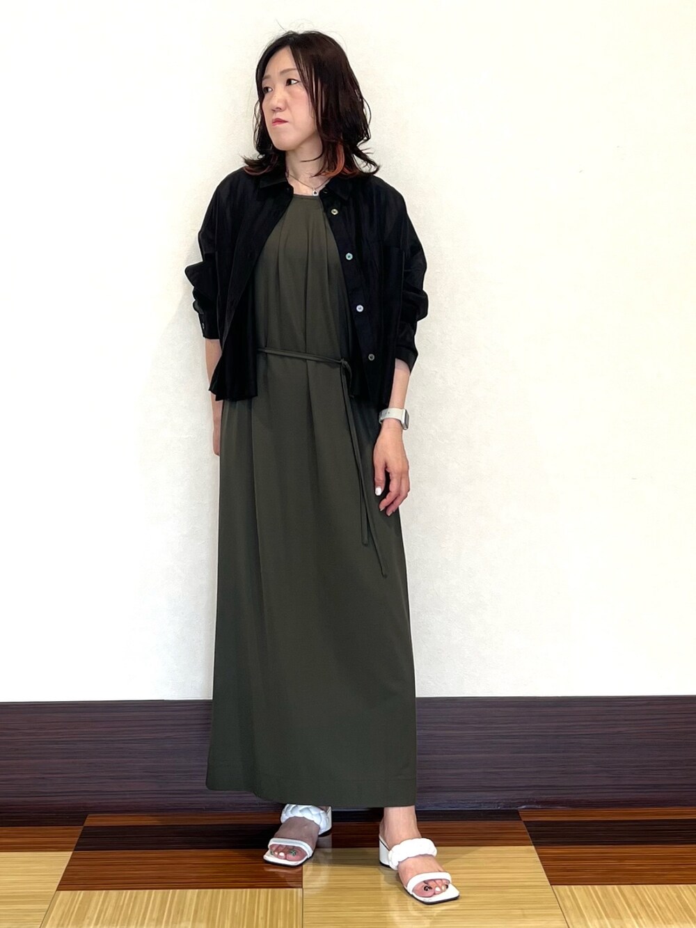 ブラック系のシャツ/ブラウス、グリーン系のワンピース、ホワイト系のサンダルを着用したレディースの夏コーディネートの2枚目の写真