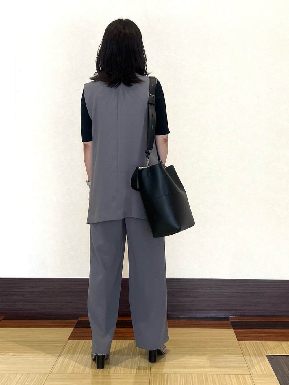 ブラック系のニット/セーター、グレー系のベスト、グレー系のスーツパンツを着用したレディースの秋コーディネートの5枚目の写真