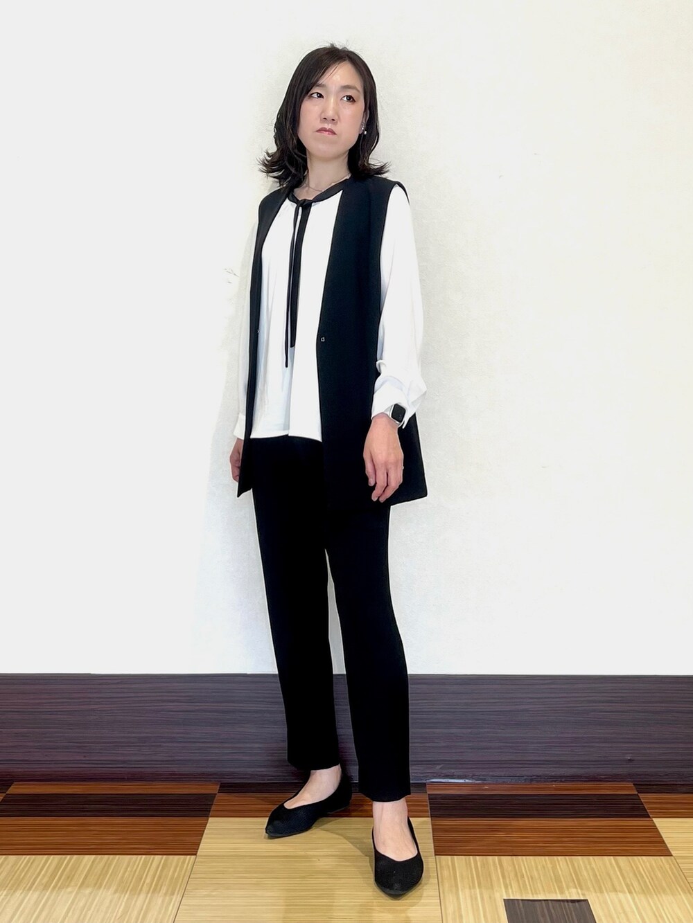 ホワイト系のシャツ/ブラウス、ブラック系のベスト、ブラック系のスーツパンツを着用したレディースの春コーディネートの2枚目の写真