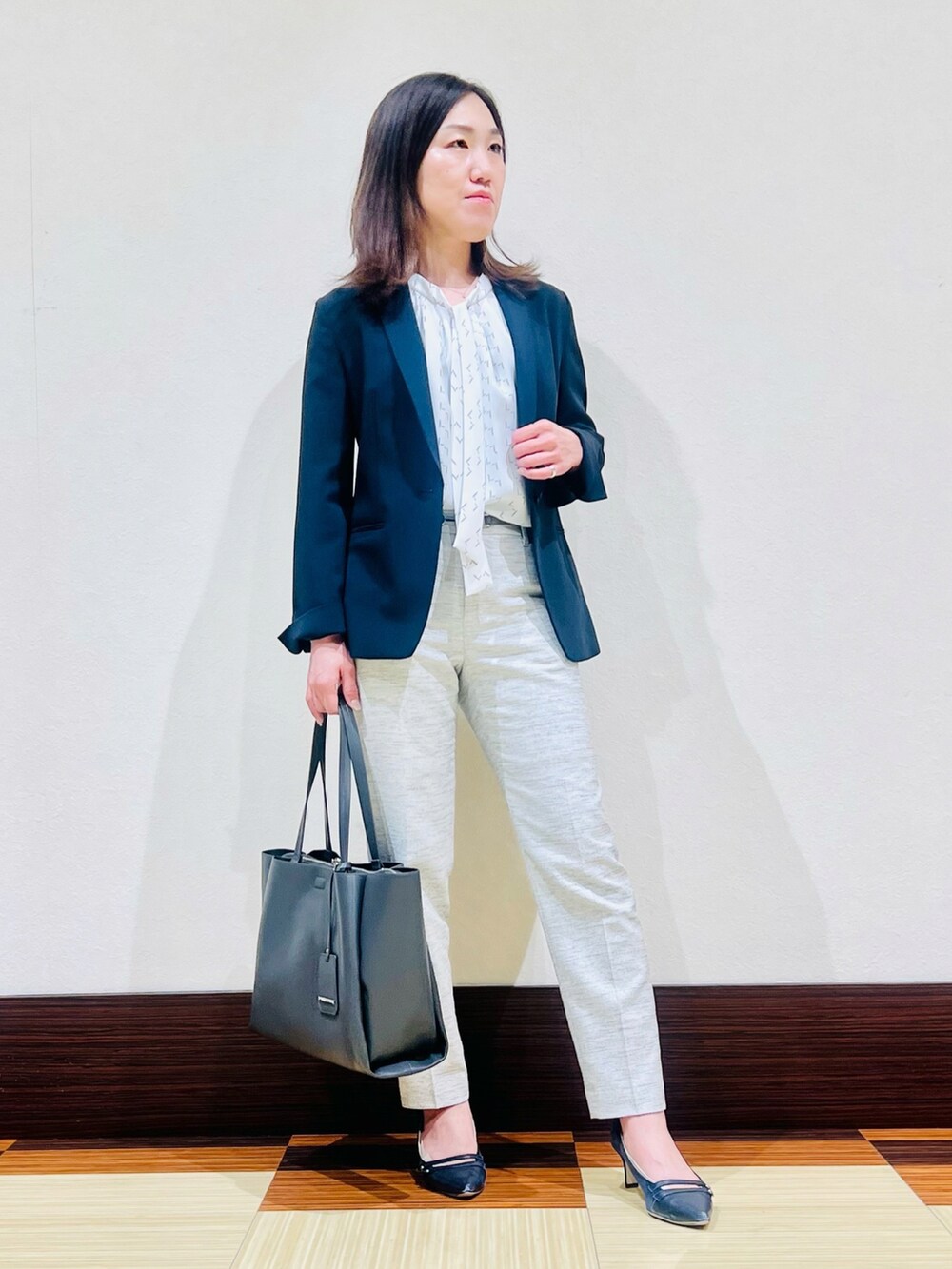 ブルー系のスーツジャケット、グレー系のシャツ/ブラウス、ブラック系のスーツパンツを着用したレディースの春コーディネートの4枚目の写真