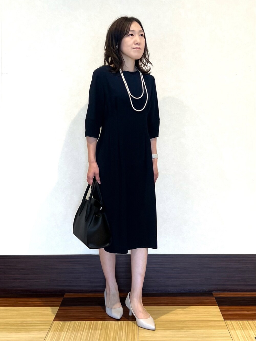 ブラック系のノーカラージャケット、ブルー系のワンピース、ホワイト系のショルダーバッグを着用したレディースの冬コーディネートの5枚目の写真