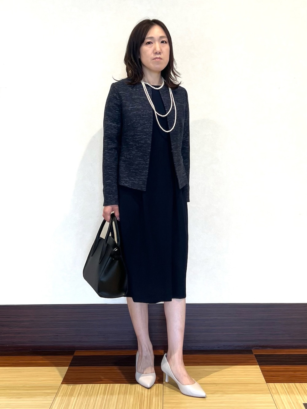 ブラック系のノーカラージャケット、ブラック系のワンピース、ブラック系のショルダーバッグを着用したレディースの冬コーディネートの2枚目の写真