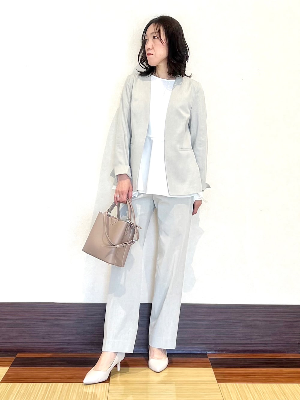 グレー系のスーツジャケット、ホワイト系のシャツ/ブラウス、グレー系のスーツパンツを着用したレディースの春コーディネートの2枚目の写真