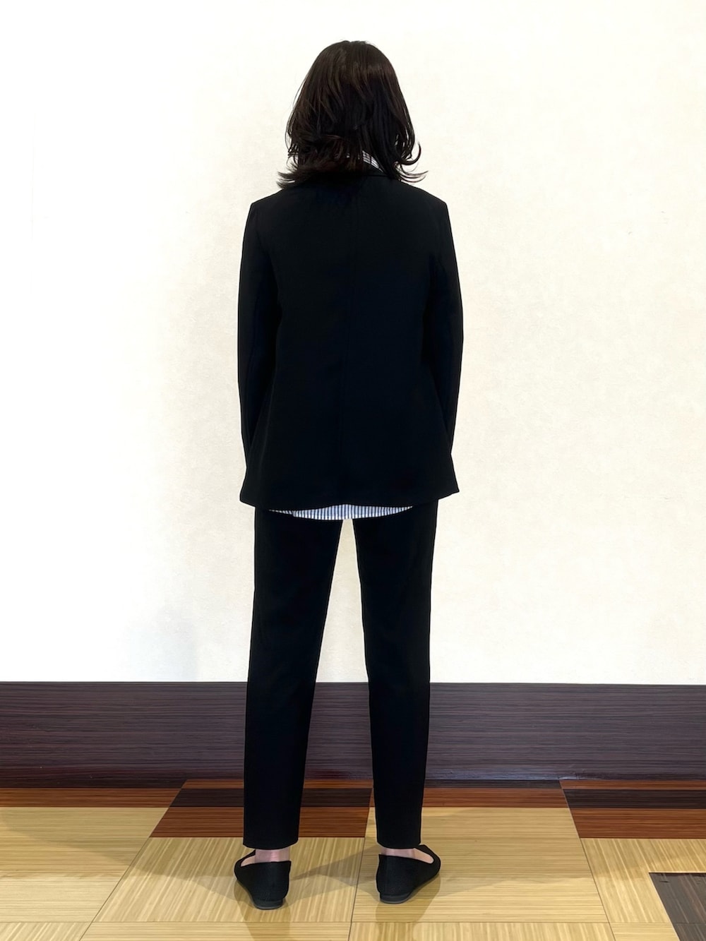 ブラック系のスーツジャケット、ホワイト系のシャツ/ブラウス、ブラック系のスーツパンツを着用したレディースの春コーディネートの5枚目の写真