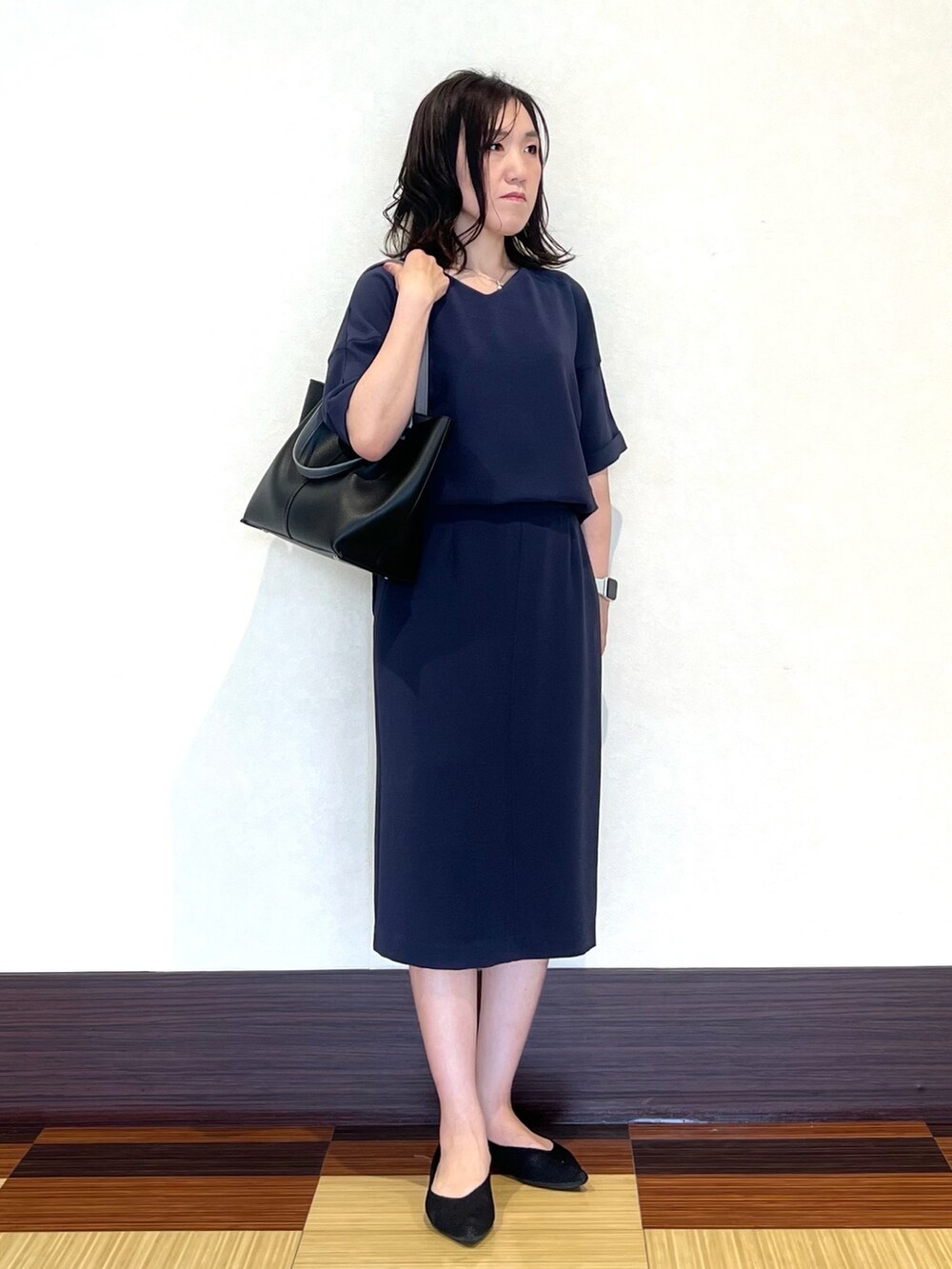 グレー系のシャツ/ブラウス、グレー系のスカート、ブラック系のパンプスを着用したレディースの春コーディネートの2枚目の写真