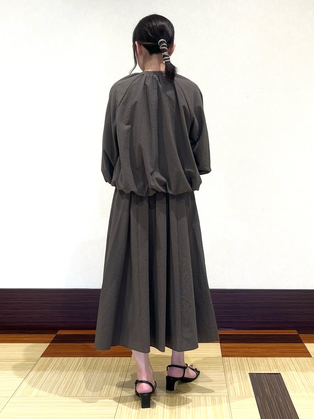 ブラウン系のワンピース、ブラウン系のブルゾン、ブラック系のサンダルを着用したレディースの秋コーディネートの5枚目の写真