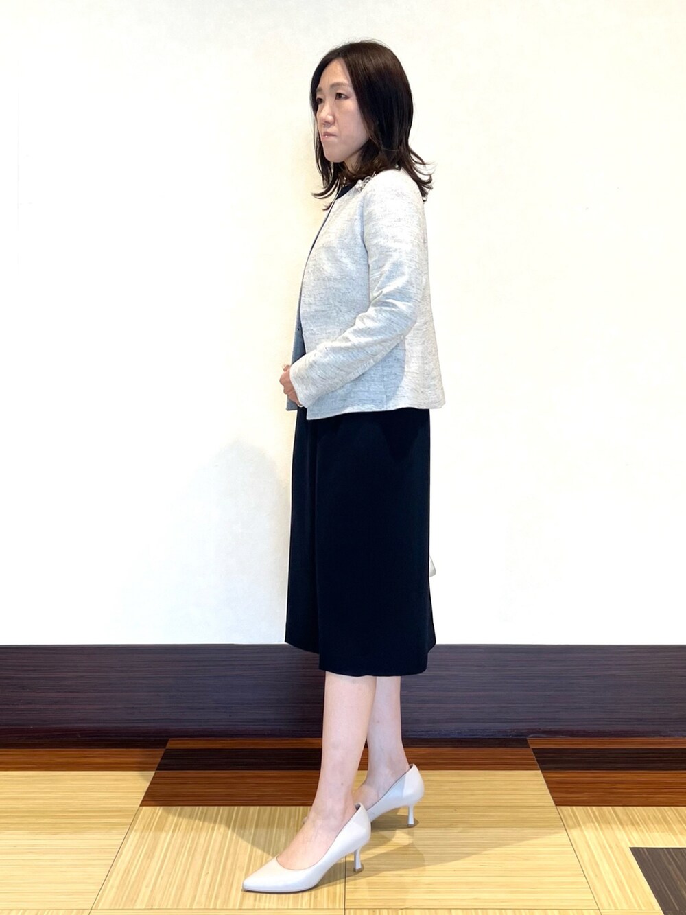 ブラック系のノーカラージャケット、ブルー系のワンピース、ホワイト系のショルダーバッグを着用したレディースの冬コーディネートの4枚目の写真